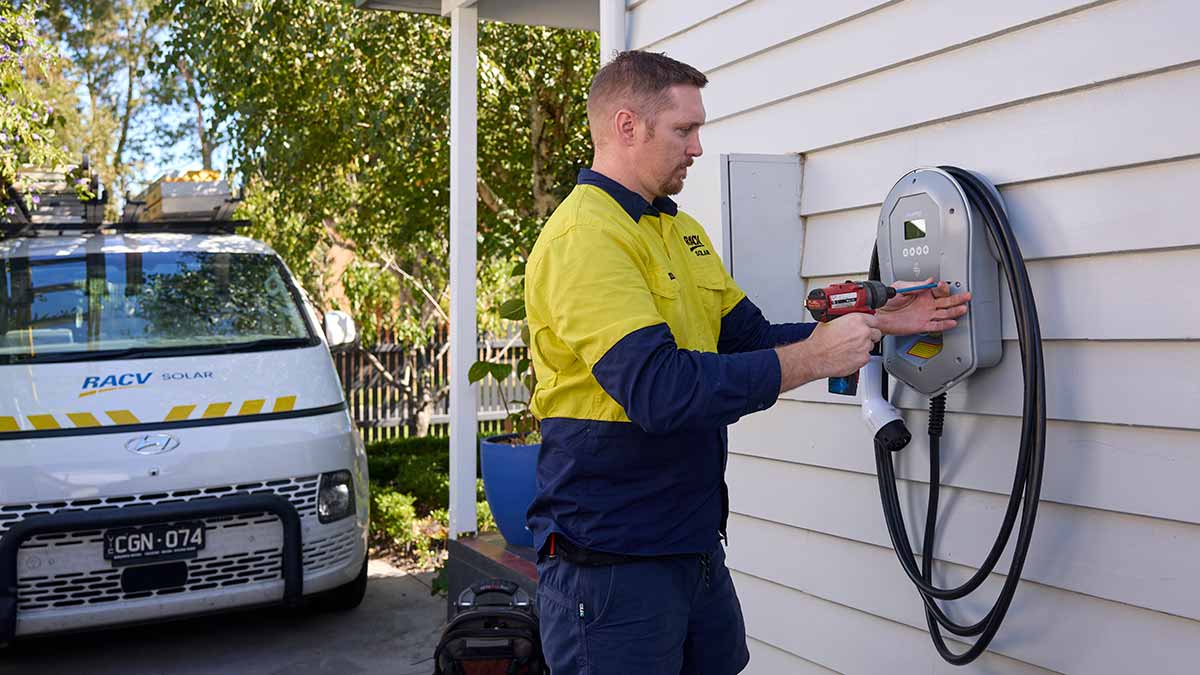 RACV tradesperson installing EV charger on wall at house in Melbourne.
