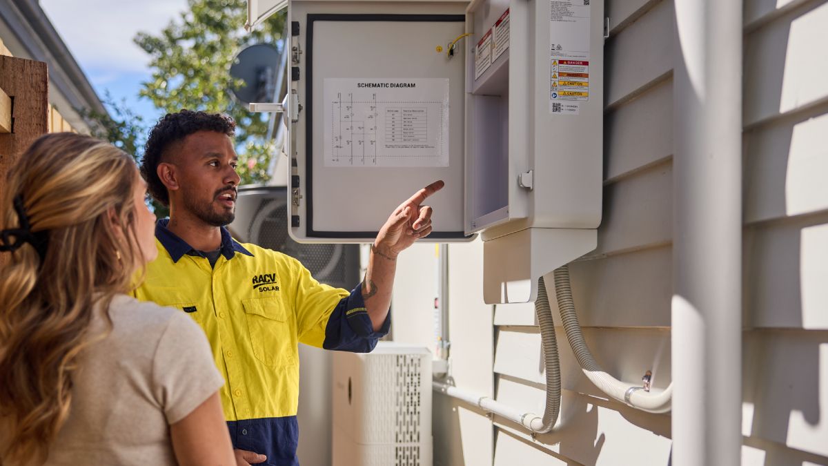 An RACV solar technician showing a homeowner the inverter connected to their solar panels and home battery