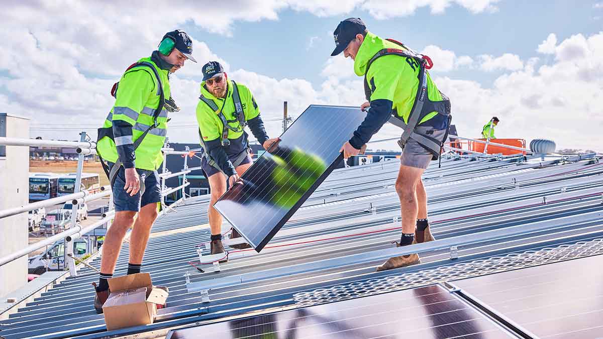 three men installing solar panels on a house roof