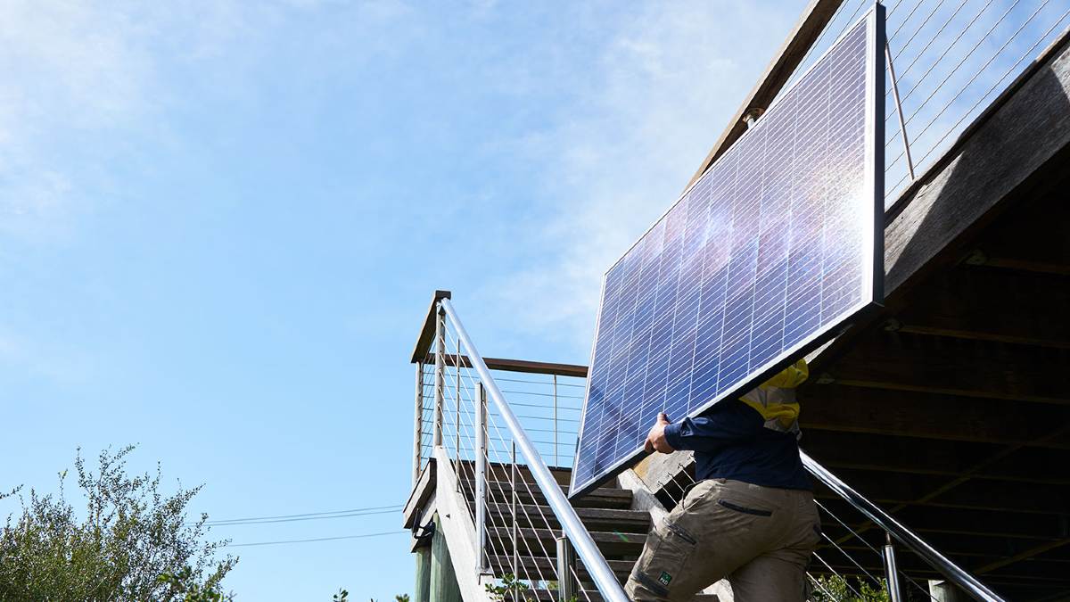Man carrying a solar panel to the roof