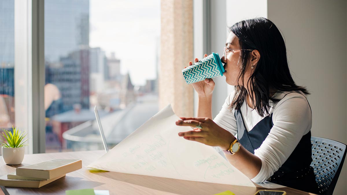 A woman drinking from a reusable coffee cup