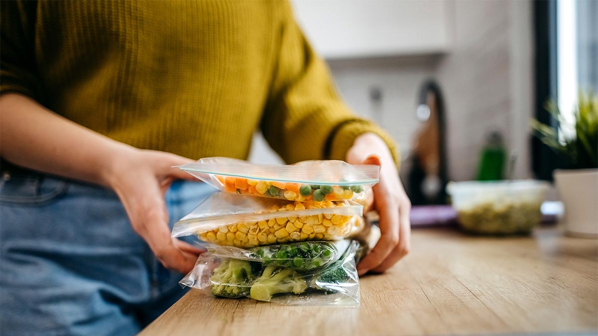 A woman putting leftover vegetables in plastic ziploc bags