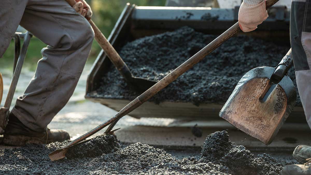 People shovelling asphalt onto a road