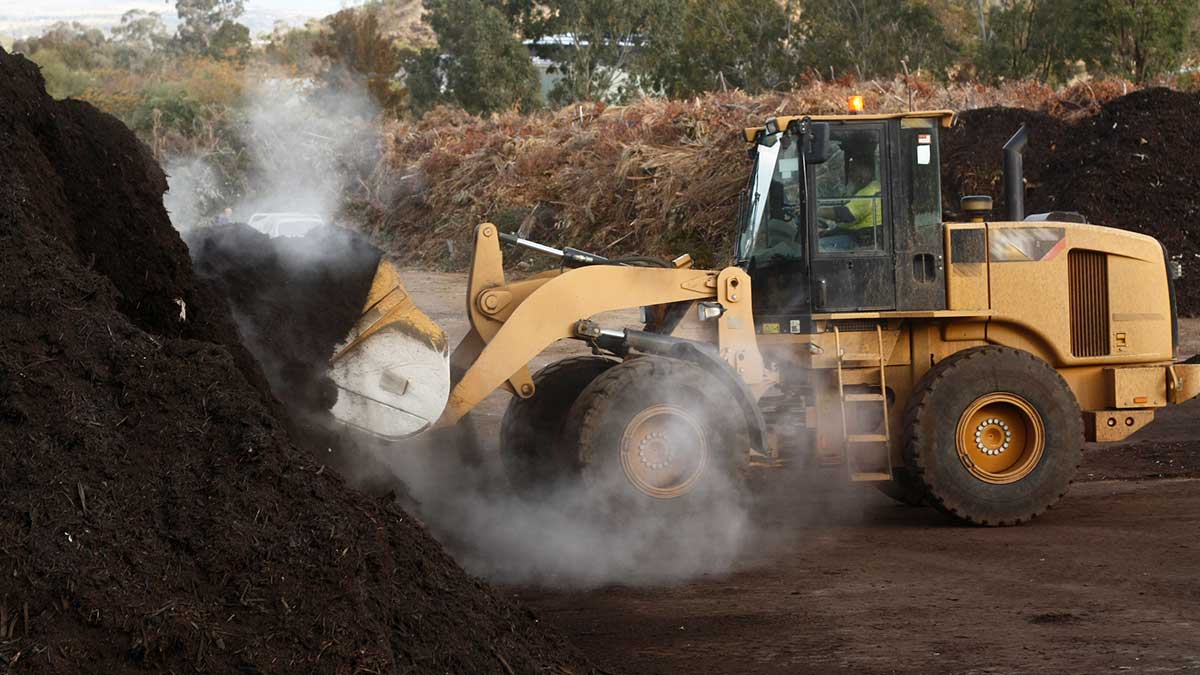 A bulldozer mixing compost at an industrial facility