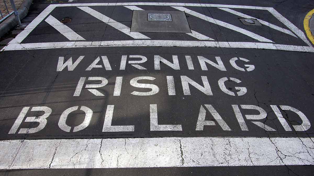 Sign painted on road, text reads-warning rising bollard