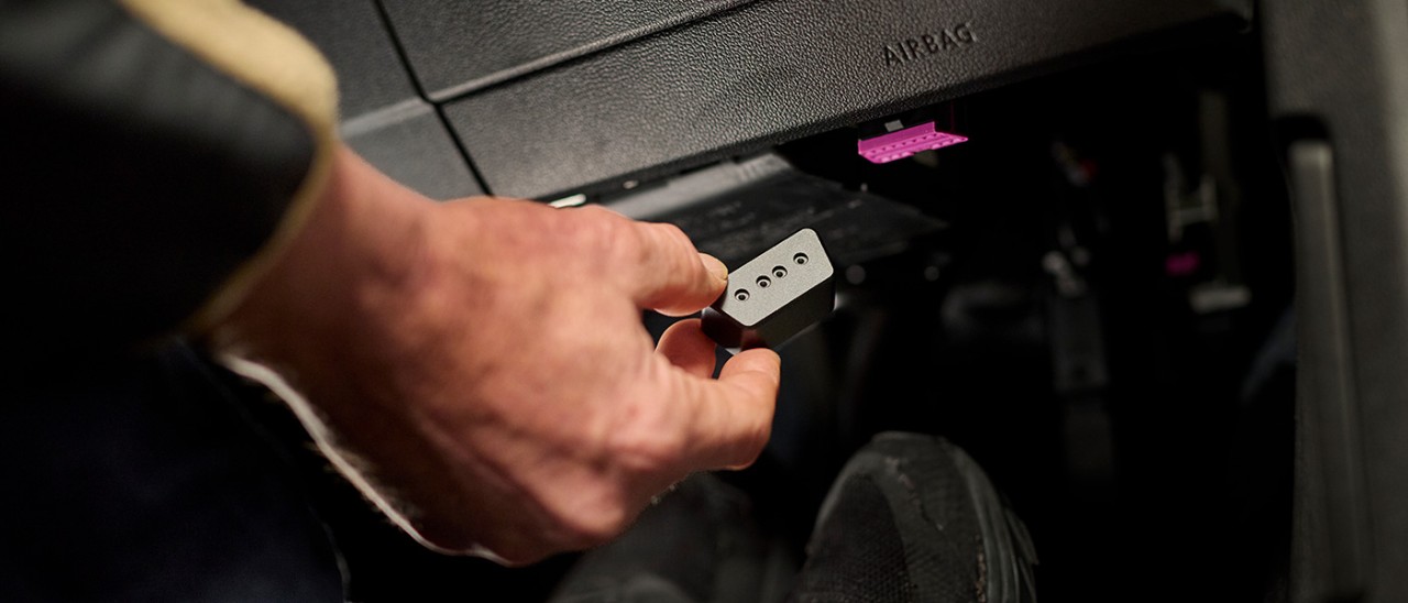Hand showing OBD lock inside car to protect against theft.