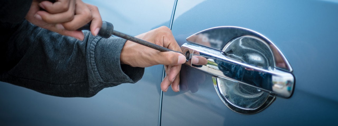 1153807413 thief trying to break into a car with a screwdriver