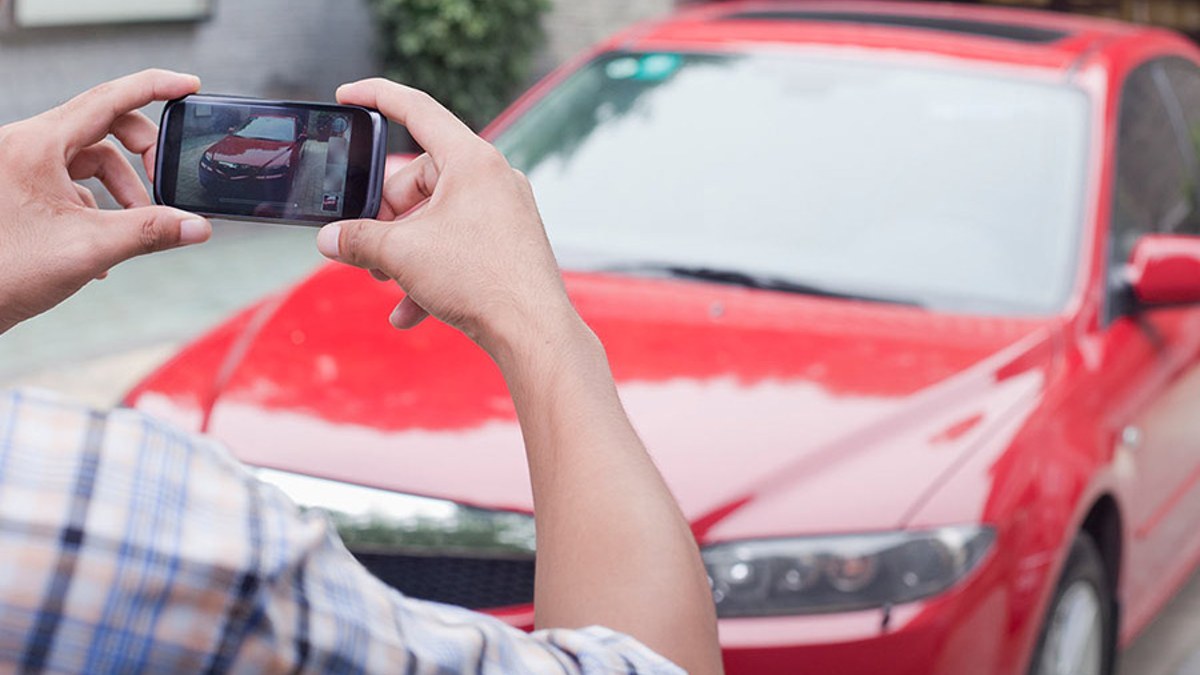man taking photo of red car