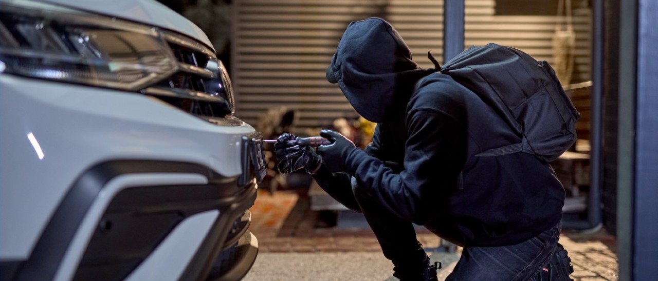 thief stealing a car's number plates