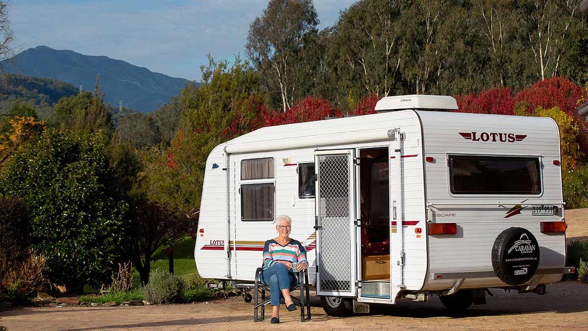 elderly woman sitting outside her caravan