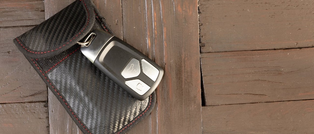 A keyless car fob sitting on top of a black Faraday pouch