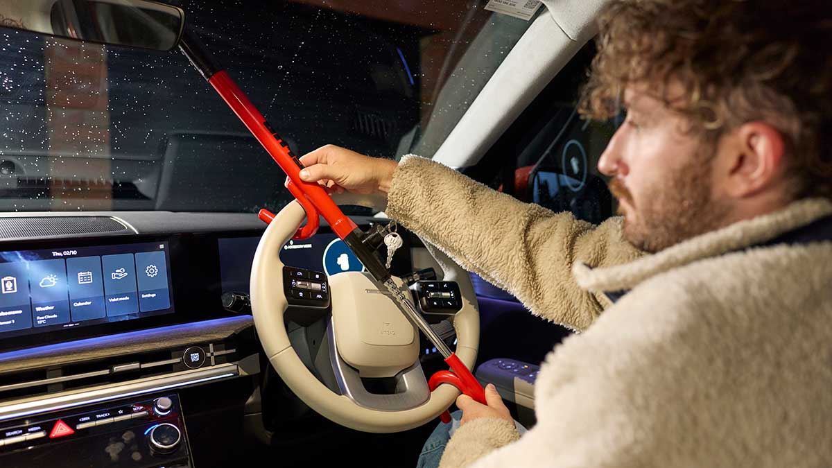 Man fitting steering wheel lock in car.