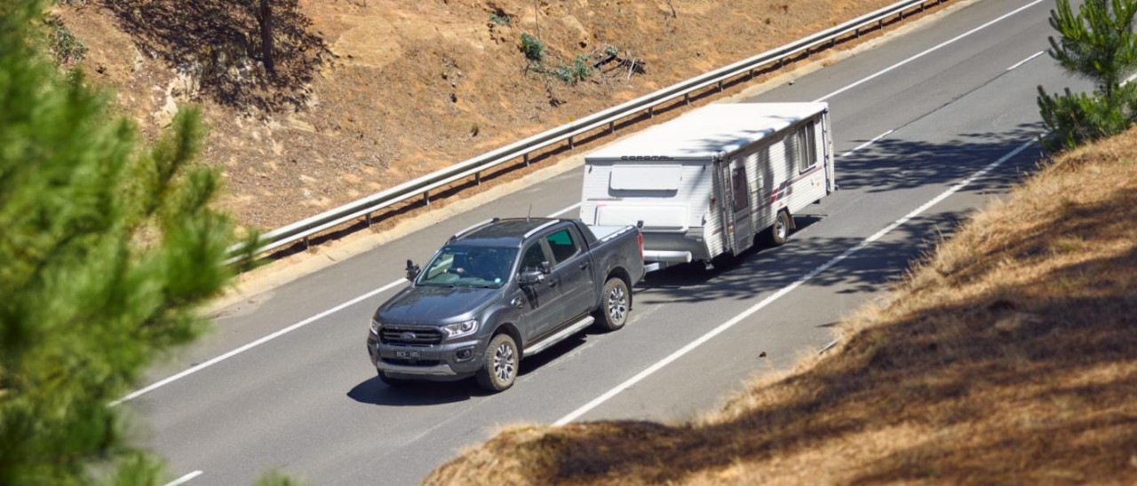 black trayback towing white caravan on road