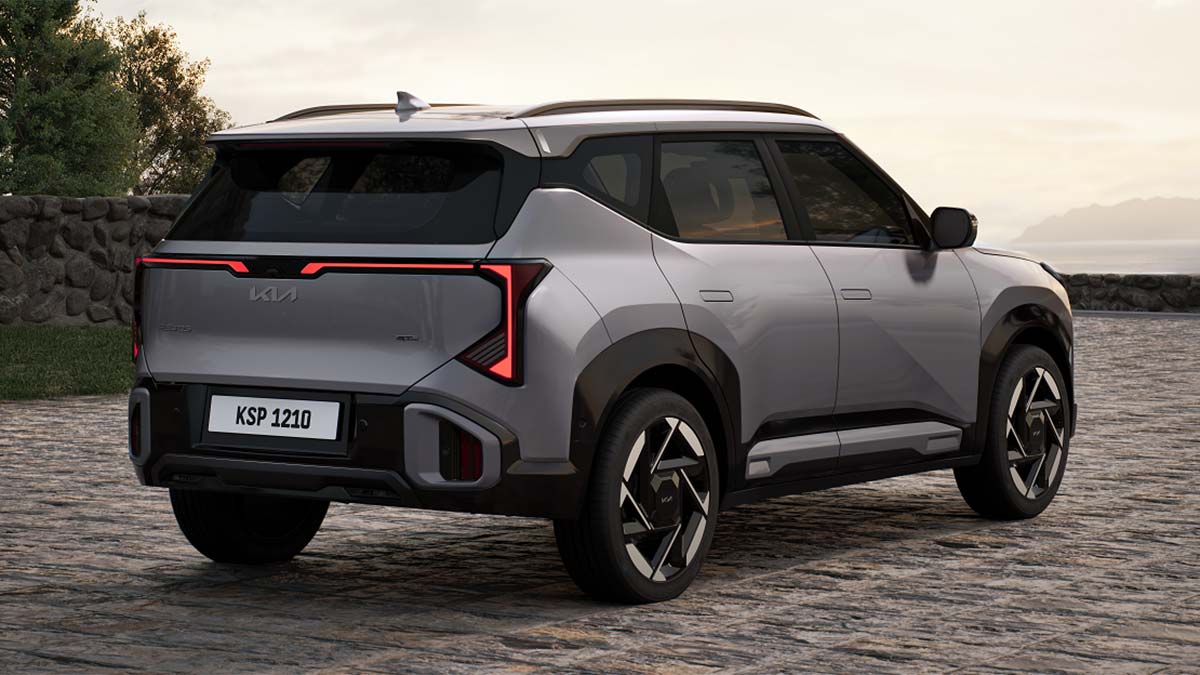 Rear view of silver Kia Seltos GT-Line SUV with wide LED tail-lights parked in courtyard in front of ocean.