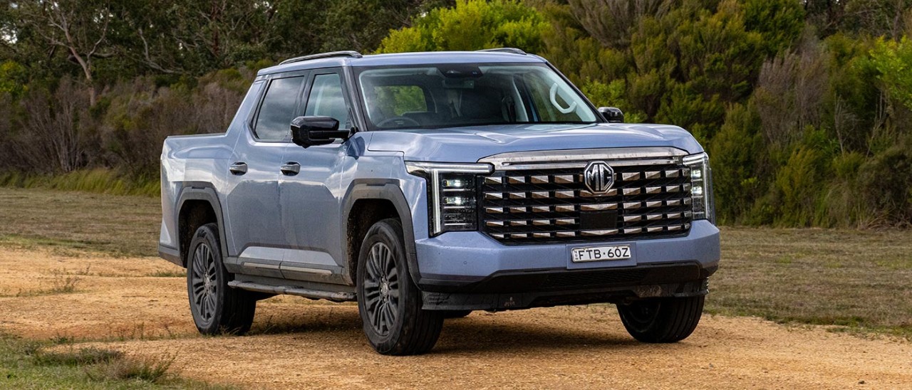 Blue MG U9 dual-cab ute on rutted track surrounded by bush.