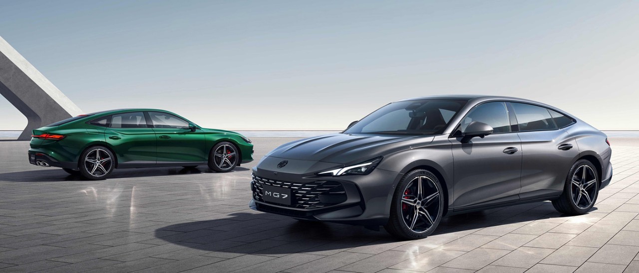 Grey metallic MG7 sports sedan in foreground and rear quarter view of green MG7 behind in open landscape.