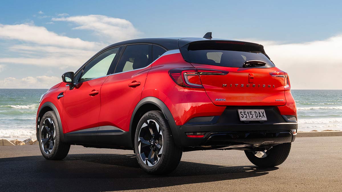 Rear view of red Mitsubishi ASX small SUV at beachfront carpark with ocean in background.
