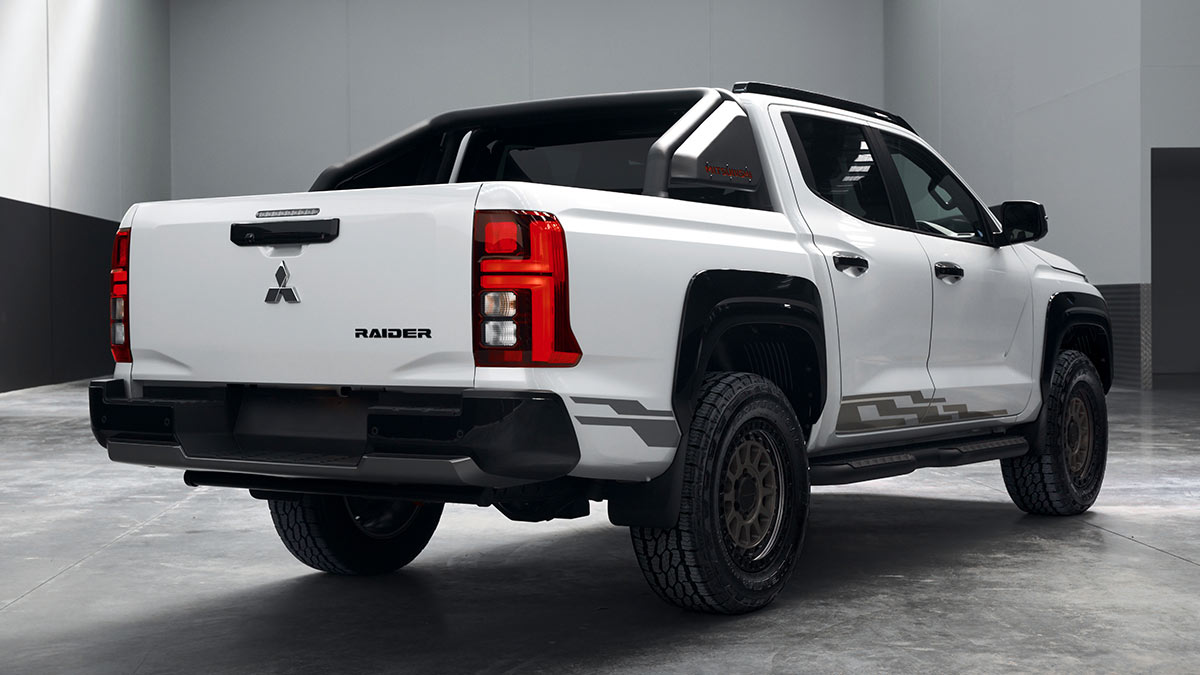 Rear view of white Mitsubishi Triton Raider dual-cab ute parked on polished concrete floor in empty warehouse.