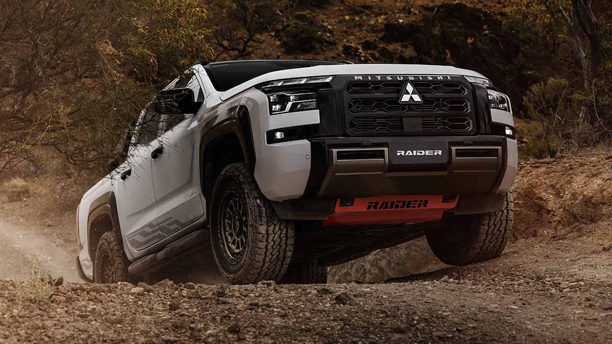 White Mitsubishi Triton Raider ute driving up steep incline on rocky off-road trail.