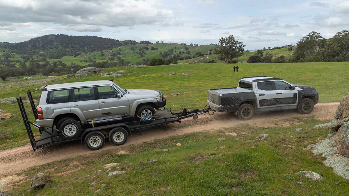 Nissan Navara ute in camouflage on rocky granite trail towing trailer with Nissan Patrol Y61 Legend Edition onboard.