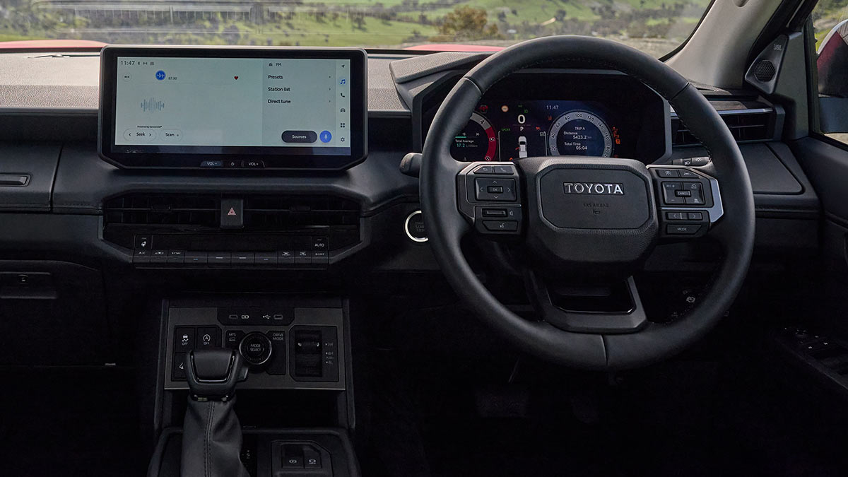 Toyota HiLux Rogue cockpit with central touchscreen, lower controls, large digital instrument display and three-spoke steering wheel.