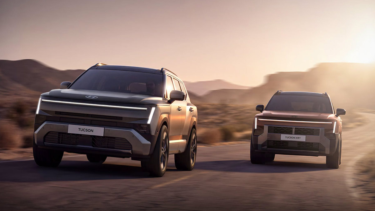 Two Hyundai Tucson SUVs driving on each side of the road on remote sunlit desert landscape.