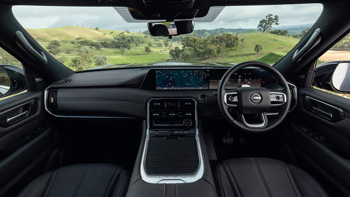 Y63 Nissan Patrol interior with large Monolith dual screens, dark interior upholstery and large centre console with metallic trim.