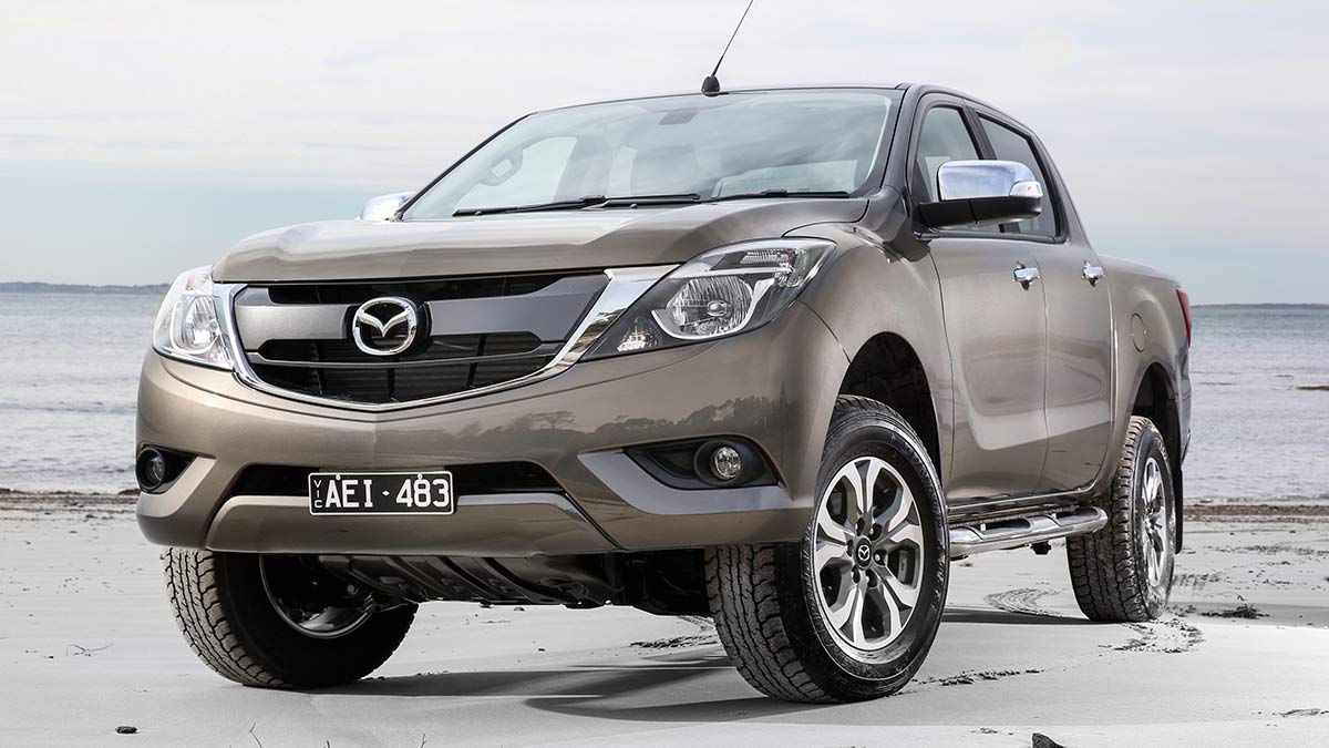 Bronze metallic 2017 Mazda BT-50 GT dual-cab ute parked on beach with white sand.