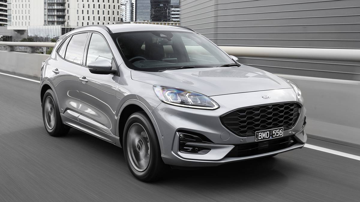 Silver Ford Escape PHEV SUV driving on Melbourne arterial road with CBD behind.