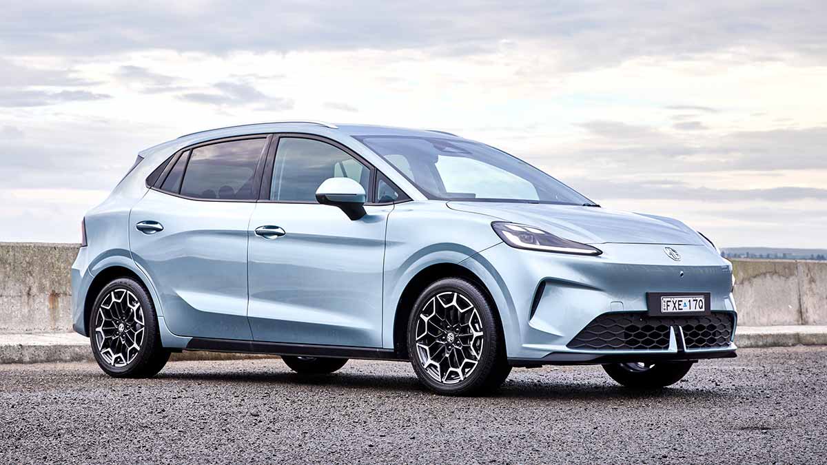 Light blue MG4 EV Urban electric hatch parked in front of concrete barrier in wide open area.