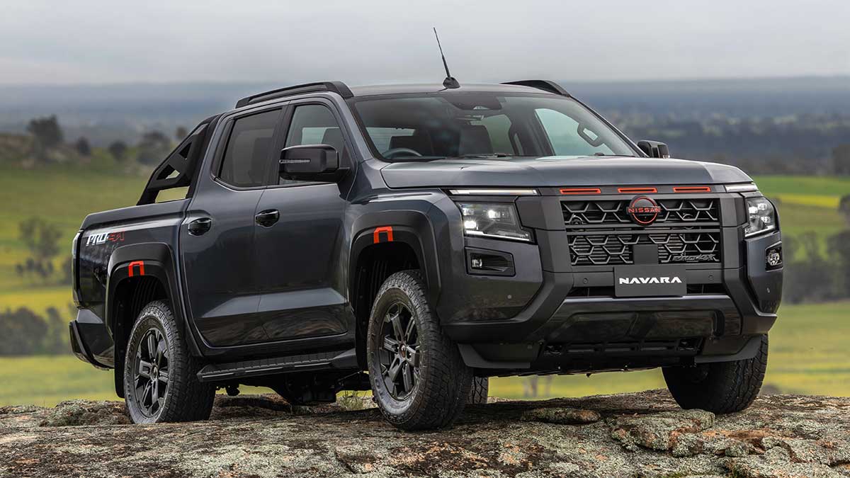 Dark grey Nissan Navara Pro-4X on rocky granite hilltop with lush green pastoral land and gum trees behind.