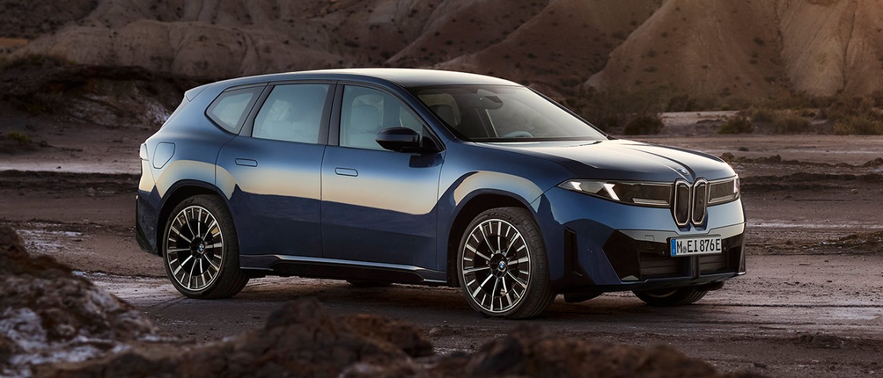 Blue BMW iX3 electric medium SUV in remote rocky mountainous location.