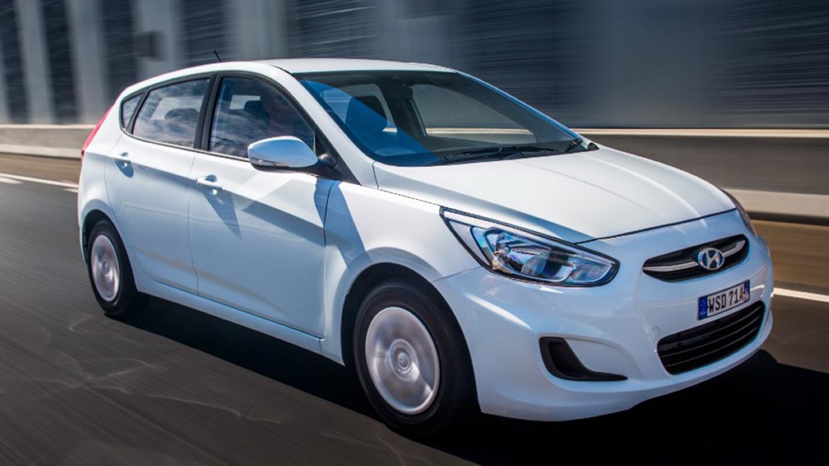 White Hyundai Accent vehicle on road.