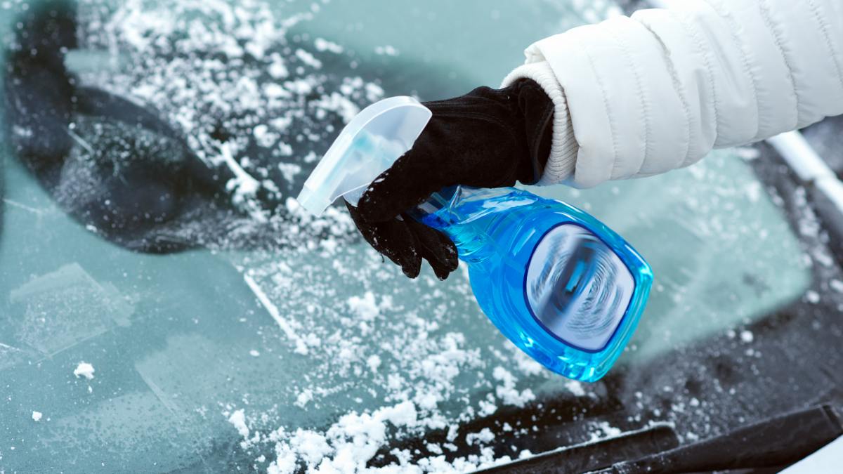 person using ice scraper on car windscreen
