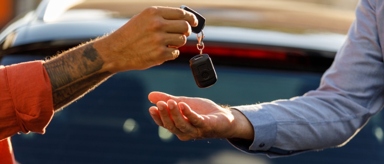 A person handing a pair of car keys to another person