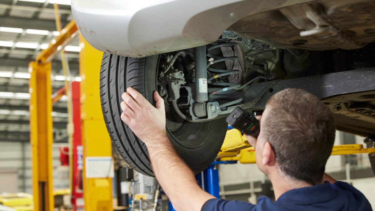 mechanic checking wheel alignment during service
