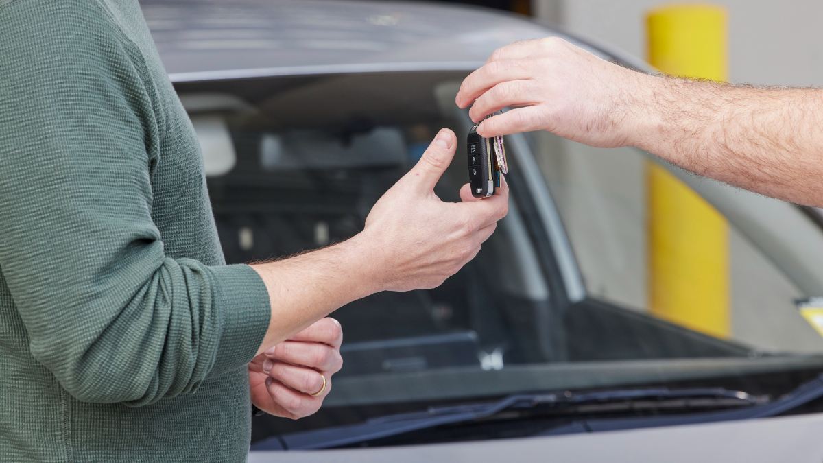 one man handing another man car keys