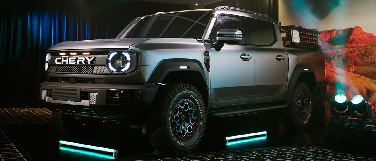 Silver design prototype of Chery KP31 ute at Sydney venue with green fluoro floor lights and Australian outback imagery behind.