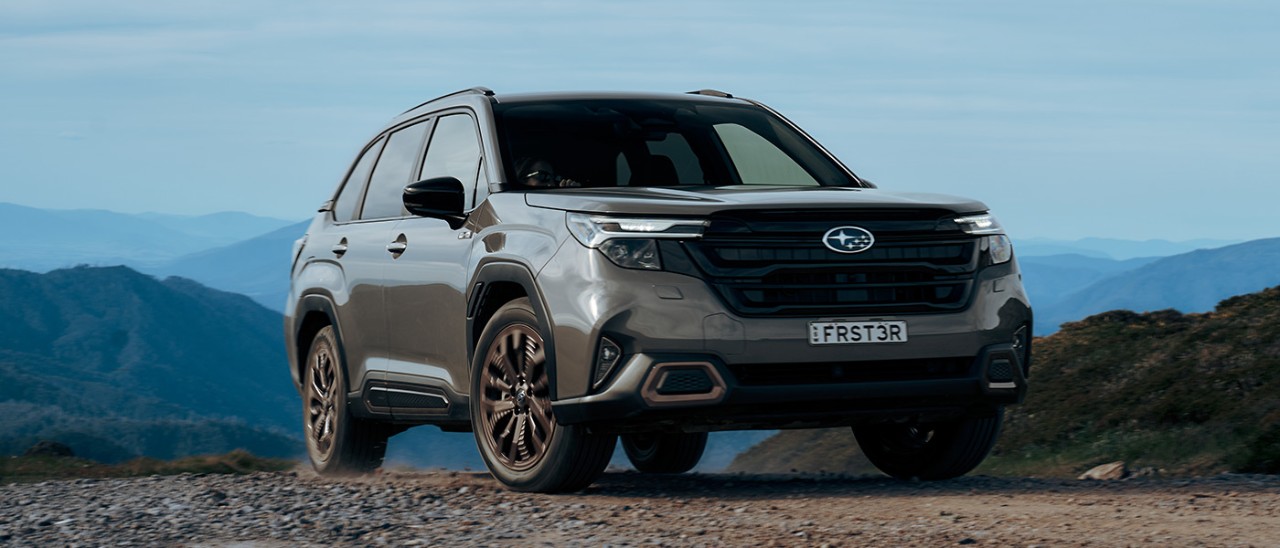 Olive green Subaru Forester Hybrid medium SUV on rocky off-road trail in Australian high country.