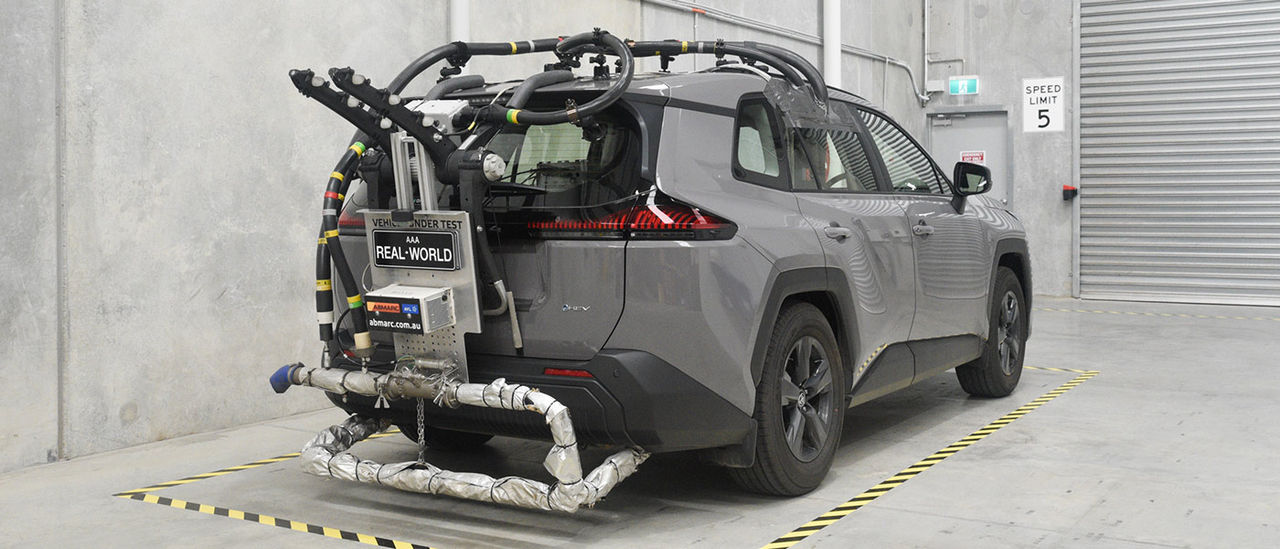 Rear view of grey metallic Toyota RAV4 rigged up with fuel economy and emissions testing equipment in warehouse, ready for real-world testing. 