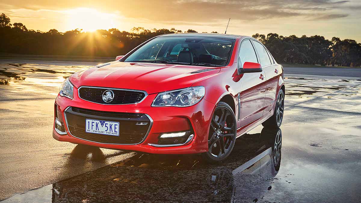A red Commodore sedan with the sunrise in the background