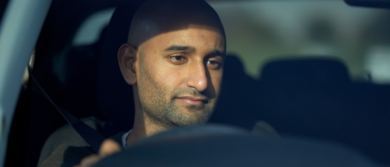 A tired-looking man with heavy eyes driving a car