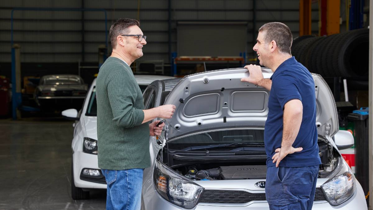mechanic speaking to car owner with car hood up