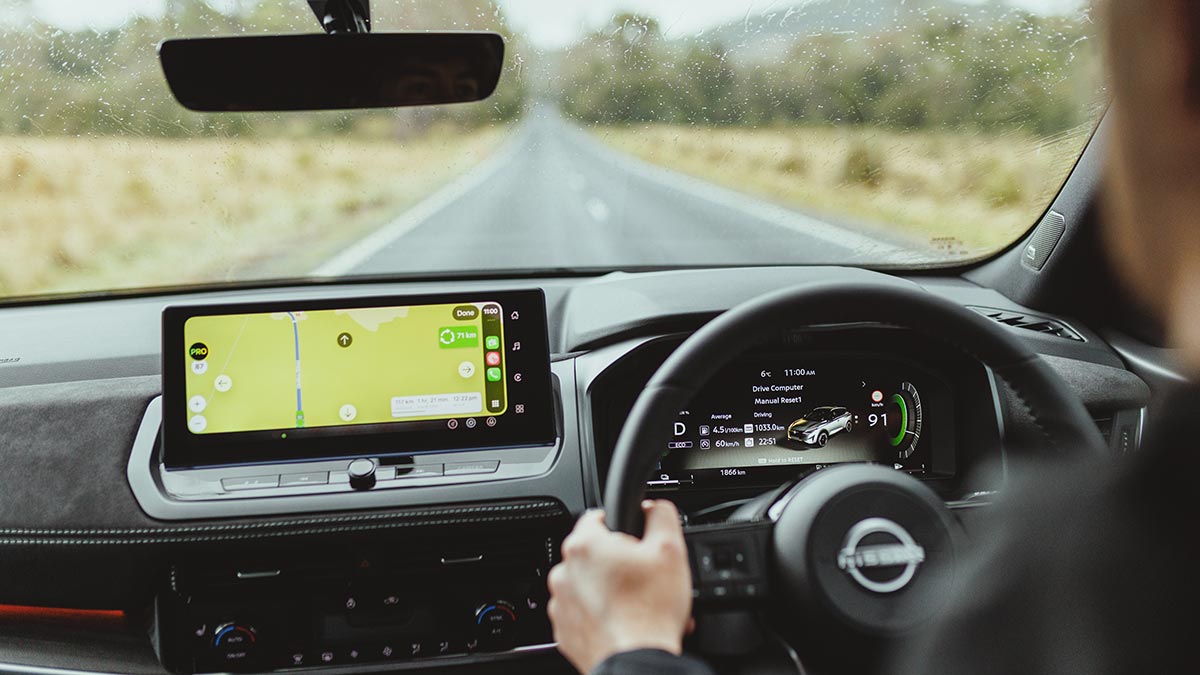 View from back seat of Nissan Qashqai SUV with driver on wet road in Tasmania.