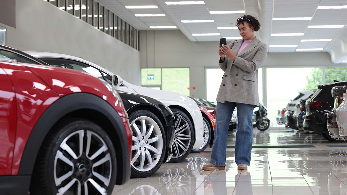 a woman takes a photo of a car in a car showroom.