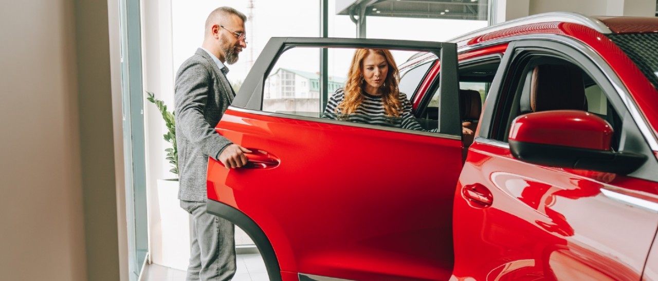 car salesman showing a female buyer a red car