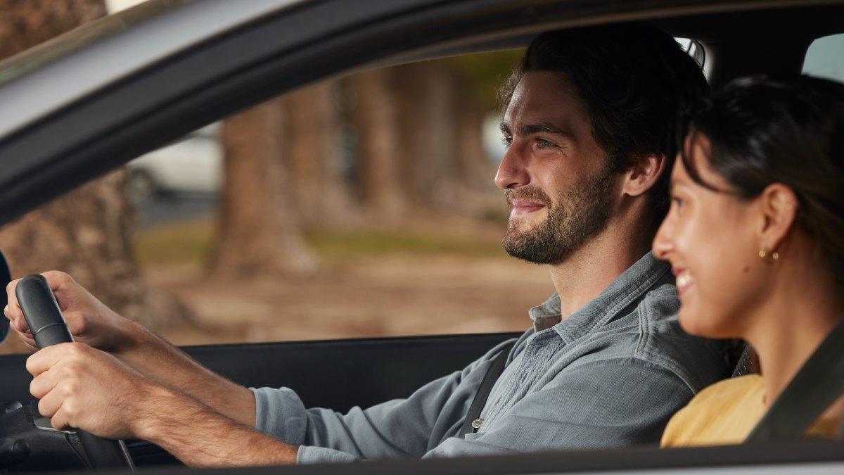 man driving car with woman in passenger seat