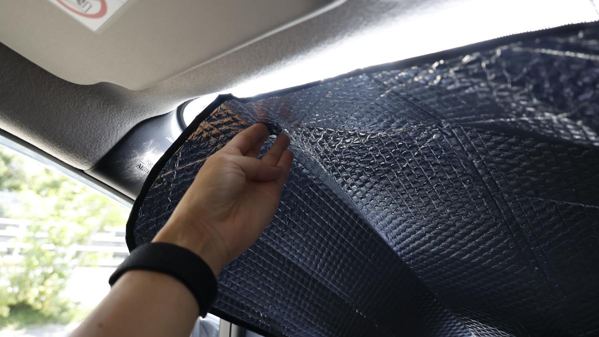 person putting up a sun reflector in their car windshield