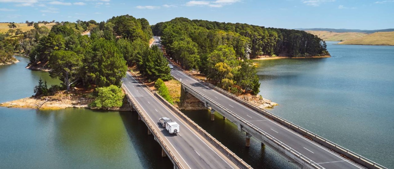 car towing caravan on a highway bridge in summer