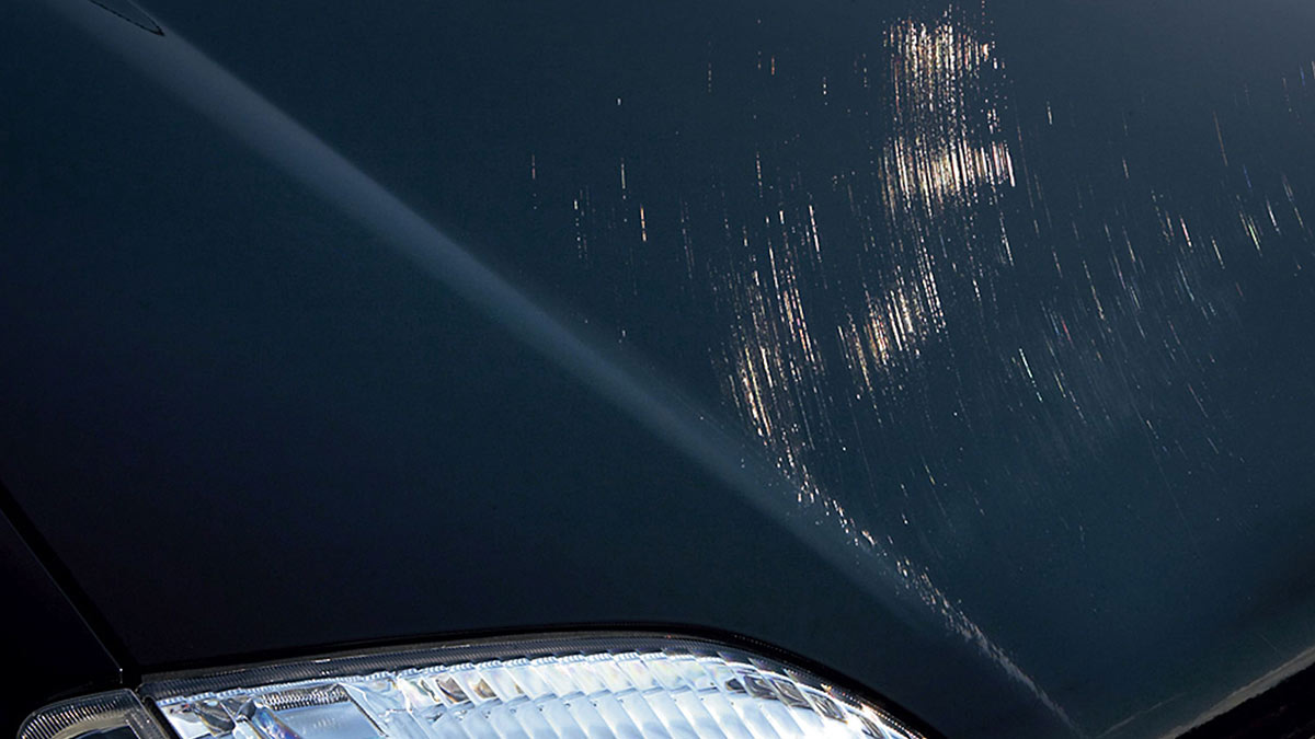 Swirling light-coloured scratches on dark blue bonnet of car